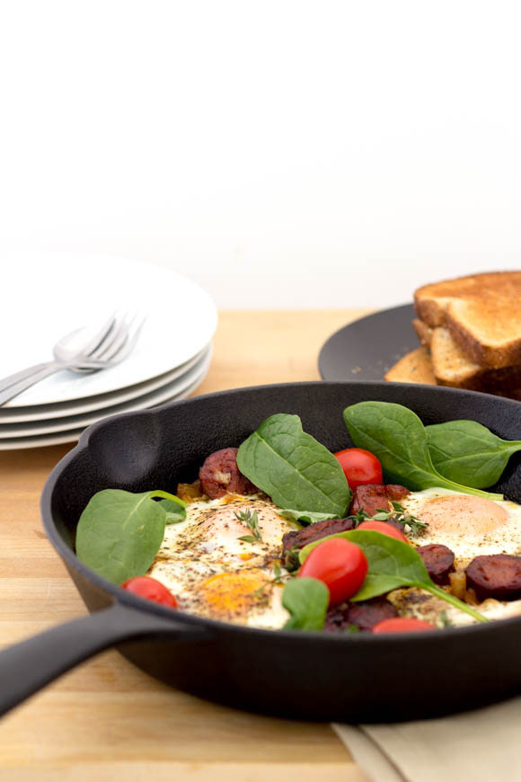 Greens, eggs, and ham fry-up served in a cast iron pan.