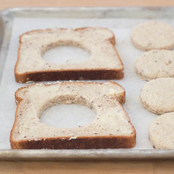 Slices of bread on a pan with the centers cut out.