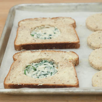 Slices of toast with spinach ricotta mixture placed in center of cut out.