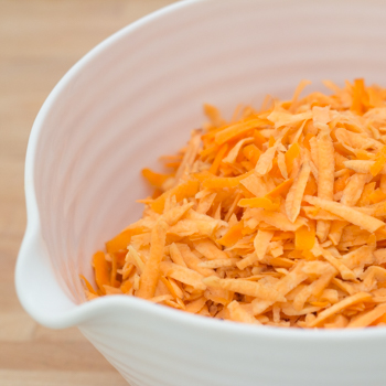 Grated sweet potatoes and carrots in a bowl.