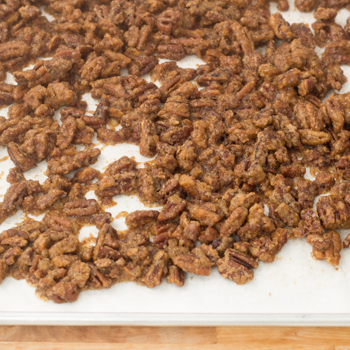 pecans being baked on a sheet with sugar.