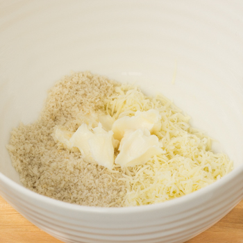 Breadcrumbs mixed with margarine and cheese in a bowl.