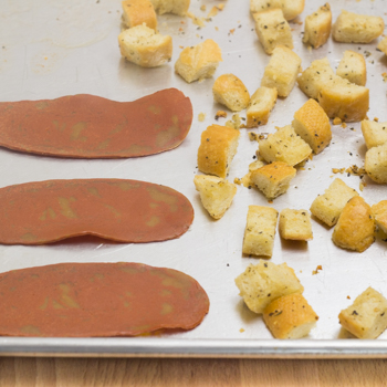 Facon, croutons on baking tray to be roasted.